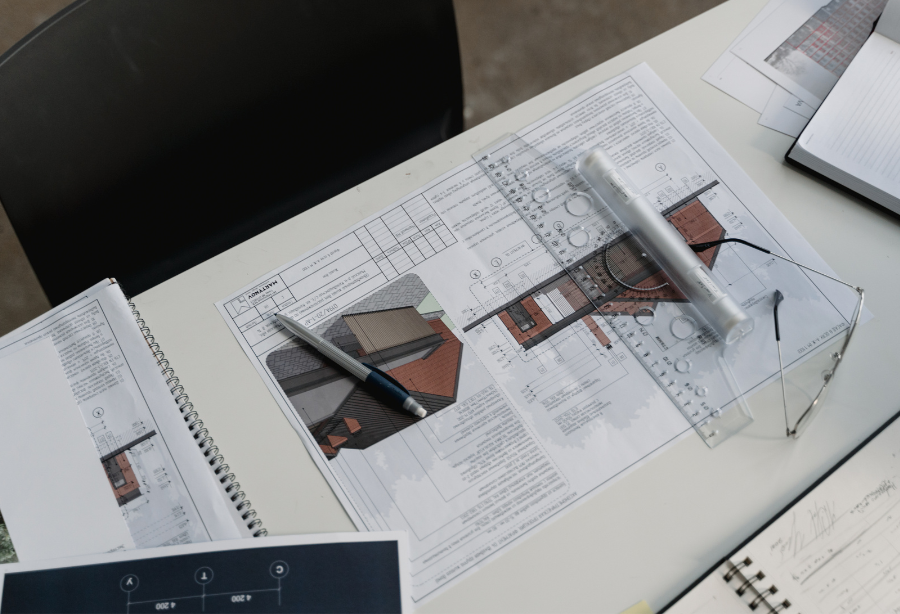  Top view of construction plans on a desk, featuring architectural drawings, a pen, and a ruler for accurate measurements